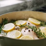 A beautiful Dutch oven filled with simmering water, fresh herbs, lemon slices, and plump chicken breasts, illustrating the perfect method for how long to boil chicken breast.