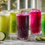 Six colorful juicing recipes for weight loss in tall glasses with fresh vegetables on marble counter