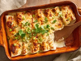 Sour cream chicken enchilada recipe in a baking dish with golden bubbly cheese green onions and cilantro