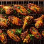 Perfectly crispy baked chicken wings in oven arranged on a wire rack over a baking sheet, garnished with fresh parsley.